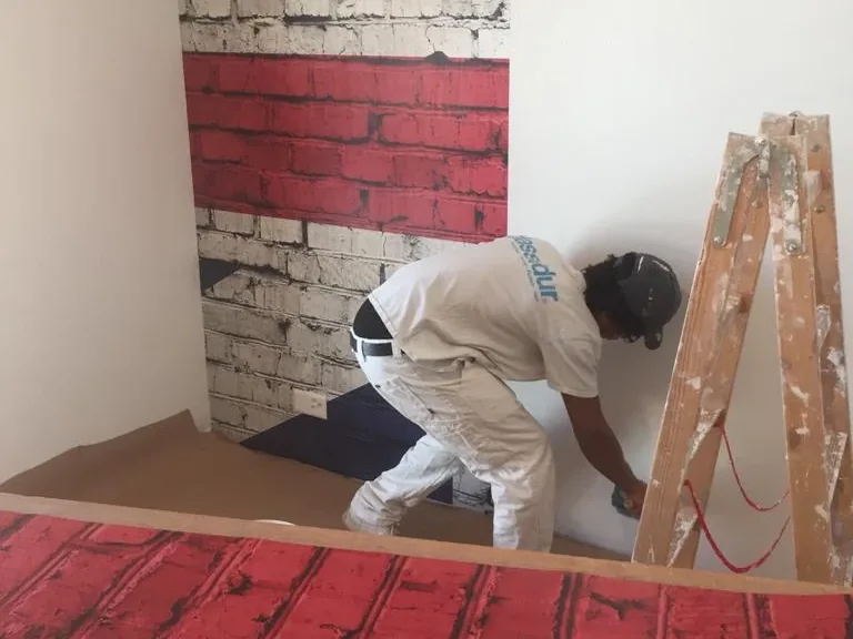 Artisan ajustant un décor mural à motifs de briques rouges et grises